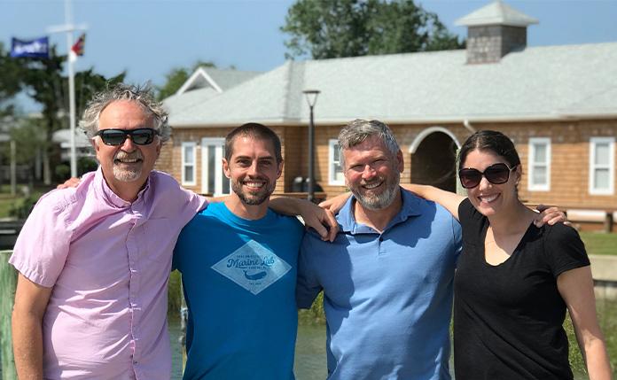 4 adults smiling and standing
