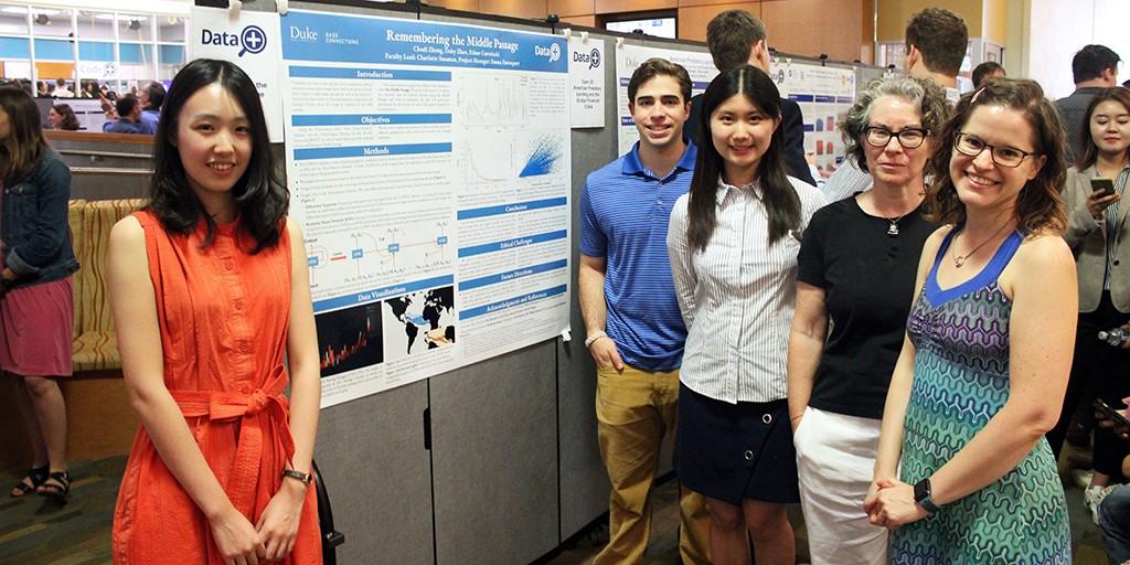 A group stands in front of their poster