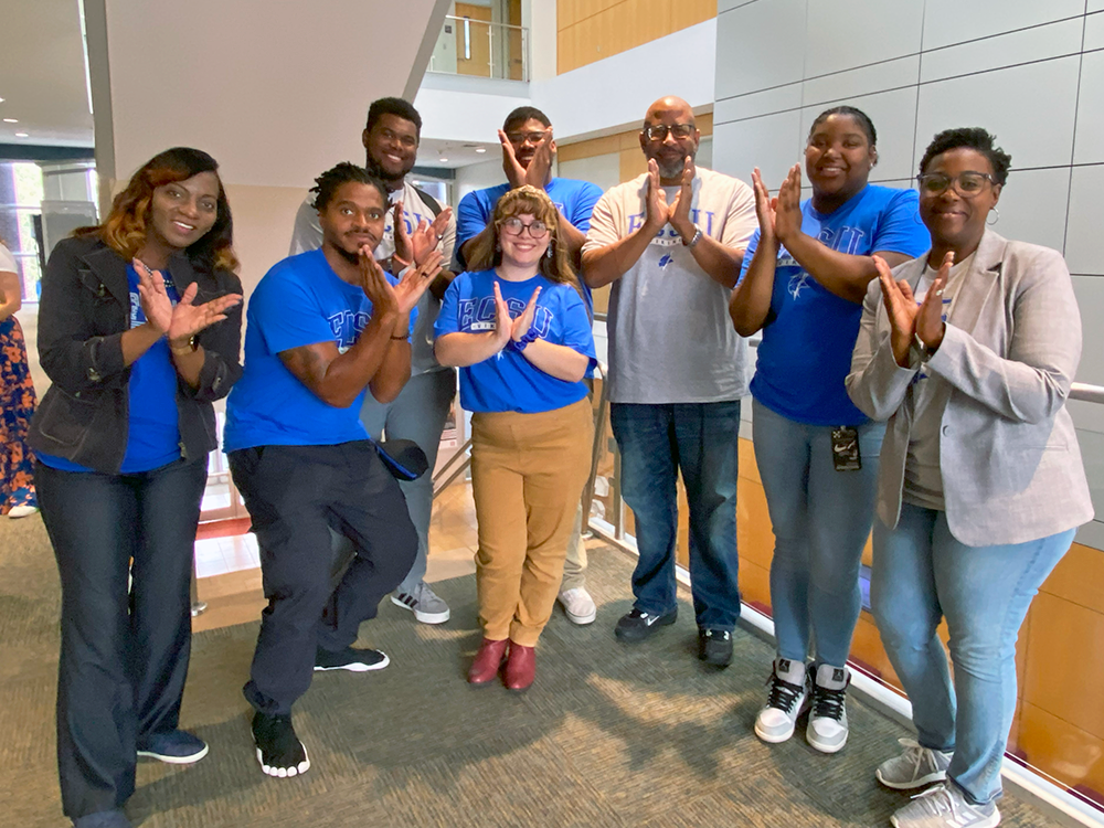 Students and faculty from ECSU make the school's Eagles symbol with their hands.