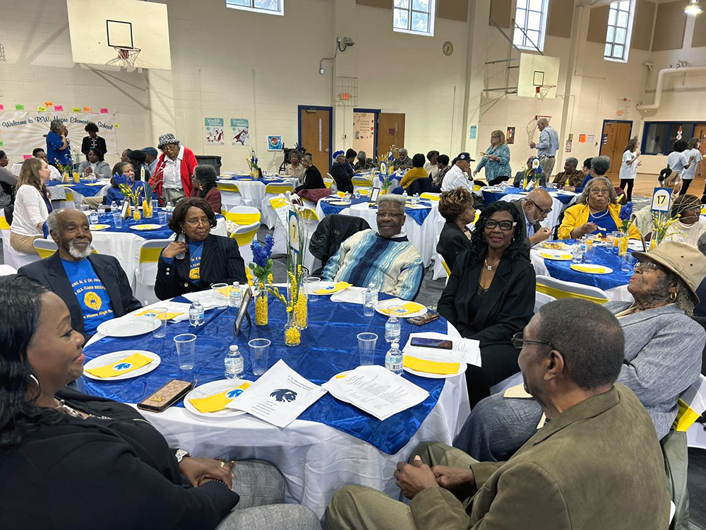 Adults gather in the P.W. Moore school gym for an alumni reunion.