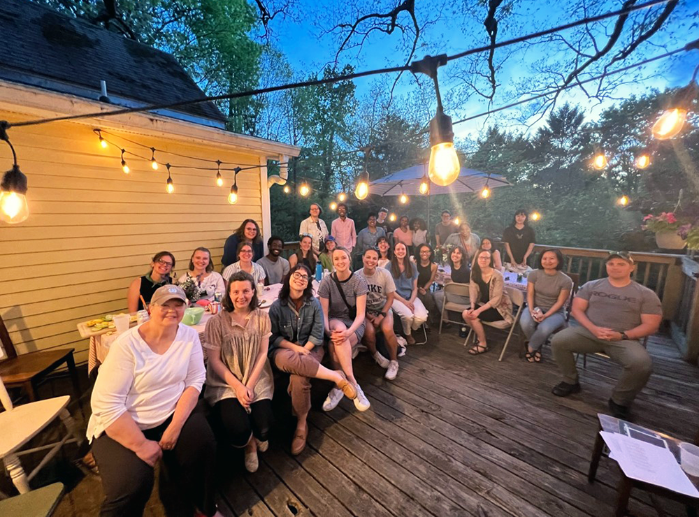 Duke professor Chris Sims' class gathers on an outdoor deck in the evening, under lights.