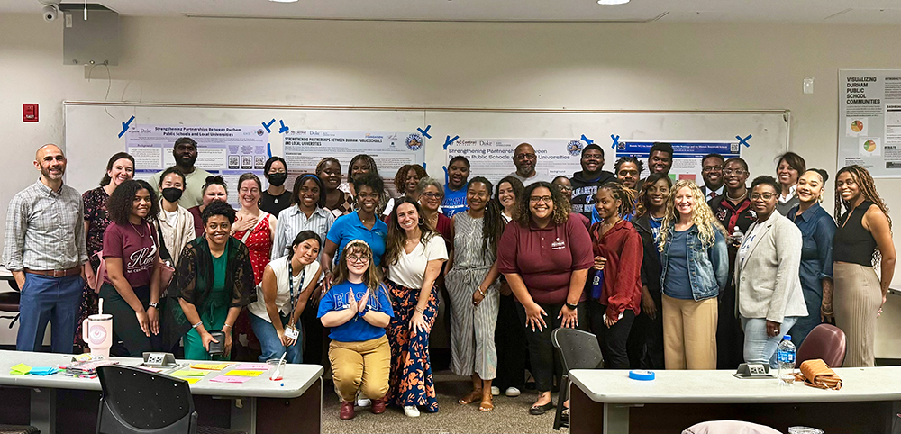 Faculty, students and administrators pose in front of research posters during a meeting at NCCU.