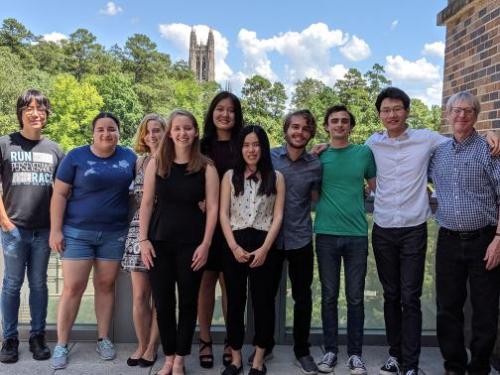 A group of students and a professor standing and smiling