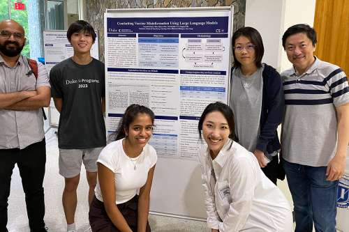 Faculty members and students pose around their team's poster.