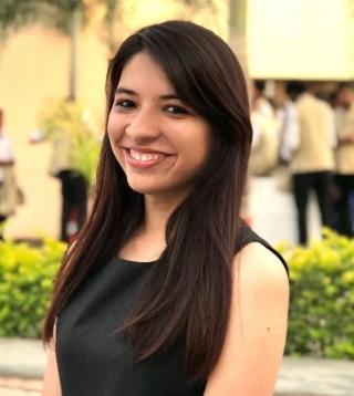 Profile image of Rewa Malhotra smiling outside with a building behind her.